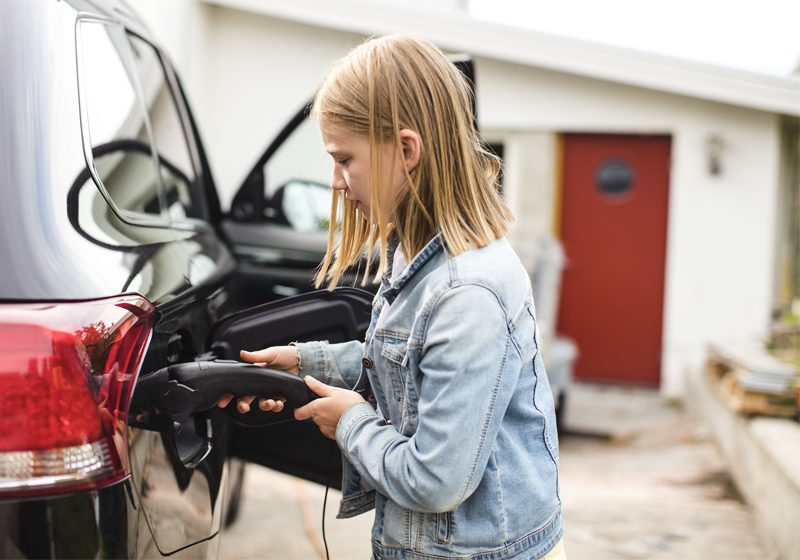Barn laddar elbil på uppfart